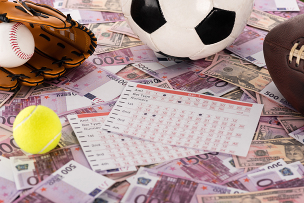 baseball kesztyű és labda, foci, tenisz és rögbi labdák közelében fogadási listák euró és dollár bankjegyek, sportfogadási koncepció - Fotó, kép