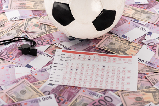 pelota de fútbol, silbato y lista de apuestas en billetes de euro y dólar, concepto de apuestas deportivas
 - Foto, imagen