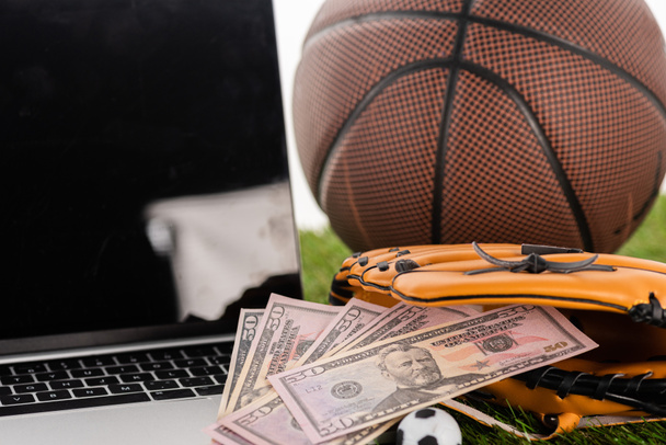 vista de cerca de billetes de dólar en guante de béisbol cerca de pelota de fútbol de juguete, portátil y pelota de baloncesto aislado en blanco, concepto de apuestas deportivas
 - Foto, Imagen