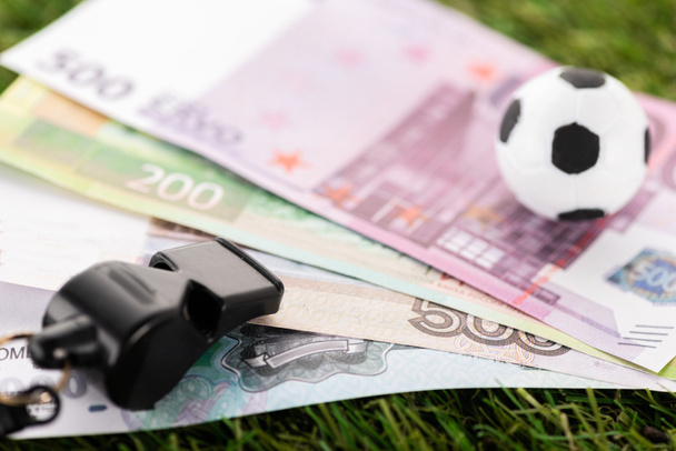 笛 おもちゃのサッカーボール 緑の芝生のユーロ紙幣 スポーツ賭博の概念の選択的焦点 ロイヤリティフリー写真 画像素材
