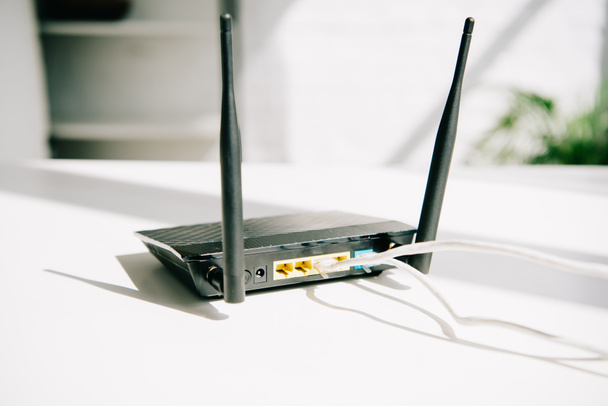 fekete dugaszolt router fehér irodai asztal napsütésben - Fotó, kép