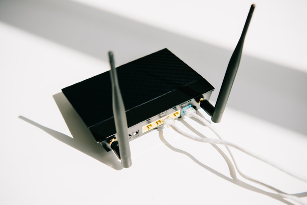 černý připojený router na bílém kancelářském stole na slunci - Fotografie, Obrázek