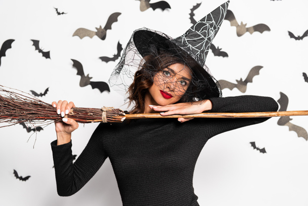 attractive woman in witch hat holding broom in Halloween - 写真・画像