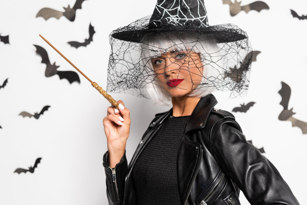 attractive woman in witch hat and wig holding magic wand in Halloween - Foto, immagini