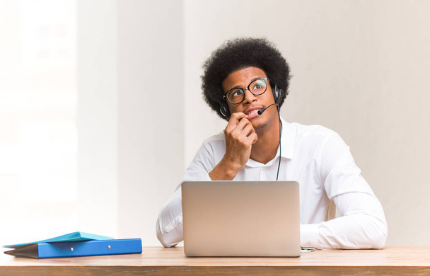 Молодой телемаркетинговый черный мужчина расслабился, думая о чем-то, глядя на копировальное пространство
 - Фото, изображение