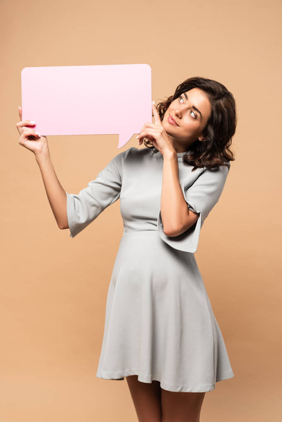 pregnant woman in grey dress holding speech bubble on beige background  - Photo, Image