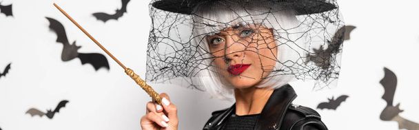 panoráma lövés vonzó nő boszorkány kalap és paróka gazdaság mágikus pálca Halloweenkor - Fotó, kép