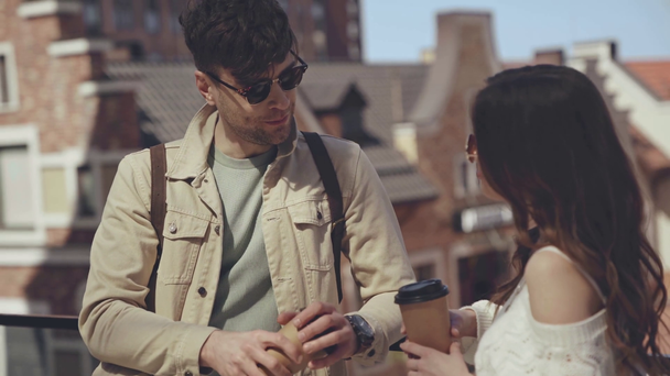 stylowy człowiek mówi w pobliżu dziewczyna z papierowym kubkiem - Materiał filmowy, wideo