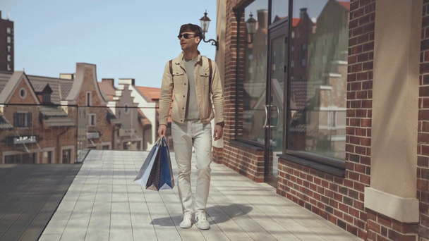 ευτυχισμένος άνθρωπος περπατώντας με τσάντες ψώνια  - Πλάνα, βίντεο