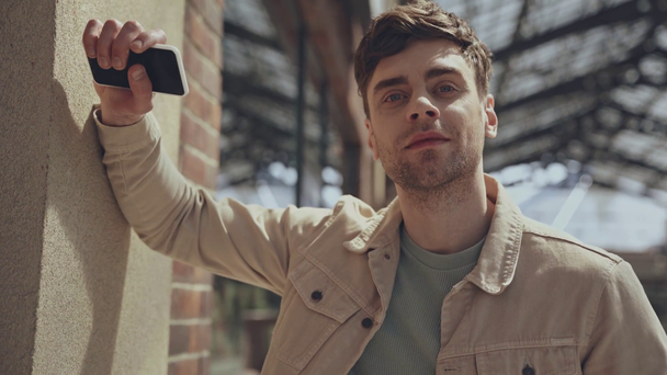 handsome man holding smartphone outside  - Кадри, відео