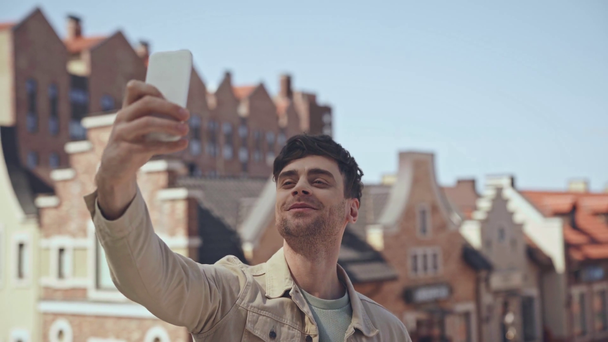 Εστίαση έλξης του ευτυχισμένος άνθρωπος gesturing, ενώ η λήψη selfie  - Πλάνα, βίντεο