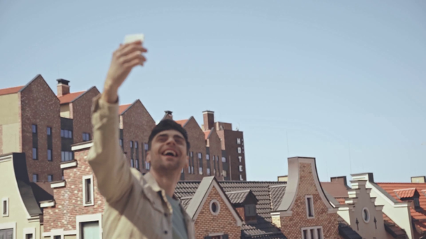 foco rack de homem feliz acenando mão enquanto segurando smartphone
  - Filmagem, Vídeo