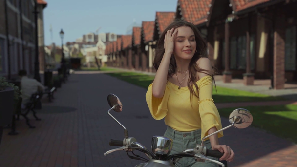 χαρούμενη γυναίκα που αγγίζει το λαιμό κοντά στη μοτοσικλέτα  - Πλάνα, βίντεο