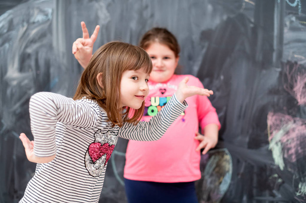 little girls having fun in front of chalkboard - Фото, зображення