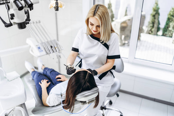 Pretty young female dentist making examination and treatment for - Zdjęcie, obraz