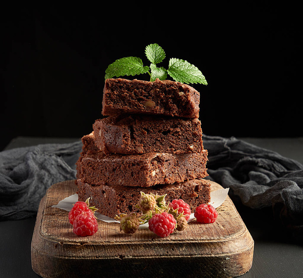 Stapel von gebackenen quadratischen Stücken Schokolade Brownie Kuchen auf braun  - Foto, Bild