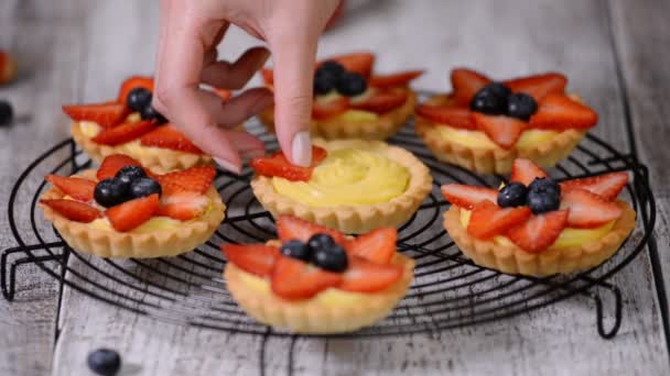 schöne leckere Sommer-Törtchen mit frischer Puddingcremefüllung mit Erdbeere und Blaubeere belegt - Filmmaterial, Video