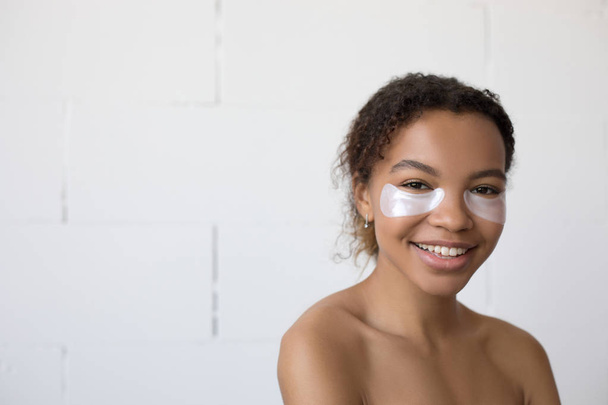 Young afro american woman with collagen pads under her eyes on white background. - Foto, Bild