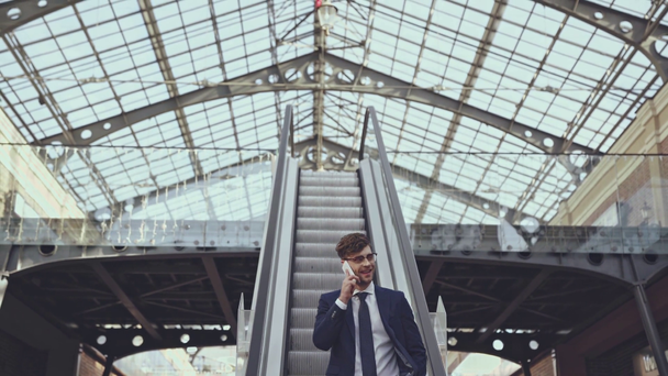 hombre de negocios alegre con smartphone en escaleras mecánicas
  - Metraje, vídeo