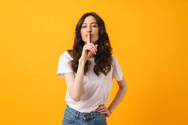 Pleased cute young woman posing isolated over yellow wall background make silence gesture. - Фото, зображення