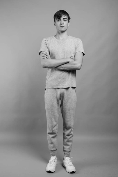 Young handsome man ready for gym against gray background - Fotografie, Obrázek
