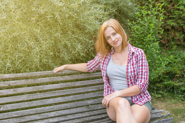 Young woman is sitting on the bench outdoors - Foto, imagen