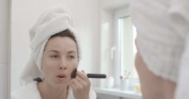 Belleza y cuidado de la piel Concepto Femenino está aplicando la fundación en su cara con un disparo de cepillo en la épica roja
 - Metraje, vídeo