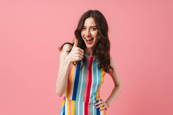 Happy positive cute woman posing isolated over pink wall background showing thumbs up. - Foto, immagini