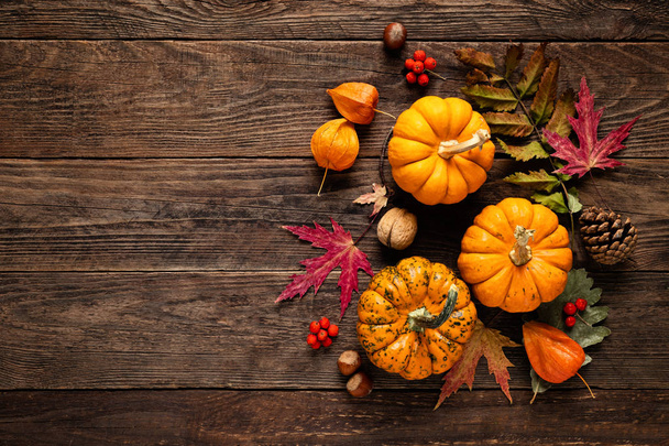 Autumn decorative pumpkins with fall leaves on wooden background. Thanksgiving or halloween holiday, harvest concept. Top view, copy space. Greeting card - 写真・画像