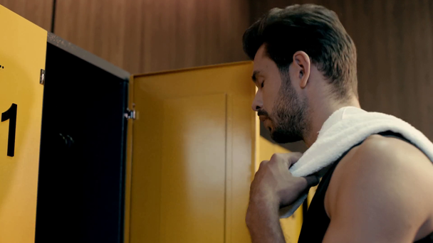 handsome sportsman taking towel in locker room  - Filmmaterial, Video