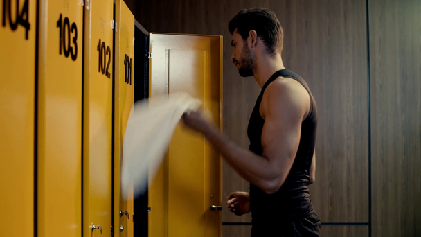 bearded sportsman taking towel in locker room  - Footage, Video