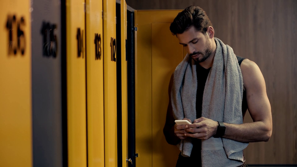 handsome man using smartphone in locker room  - Footage, Video