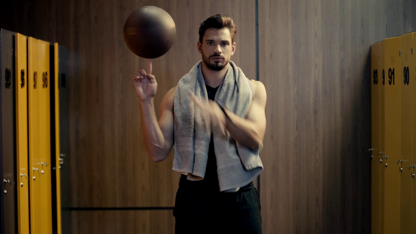 handsome sportsman spinning basketball on finger  - Materiał filmowy, wideo
