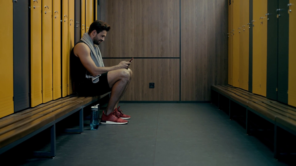 happy sportsman chatting while holding smartphone  - Кадри, відео