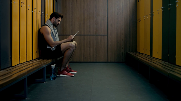 όμορφος αθλητής που χρησιμοποιεί ψηφιακό tablet στα αποδυτήρια  - Πλάνα, βίντεο
