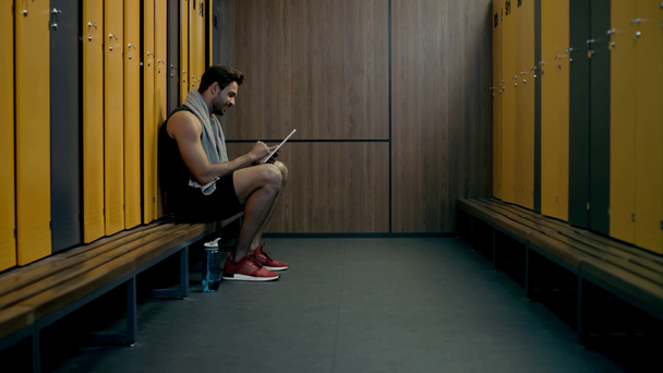 Glücklicher Sportler mit digitalem Tablet in Umkleidekabine  - Filmmaterial, Video