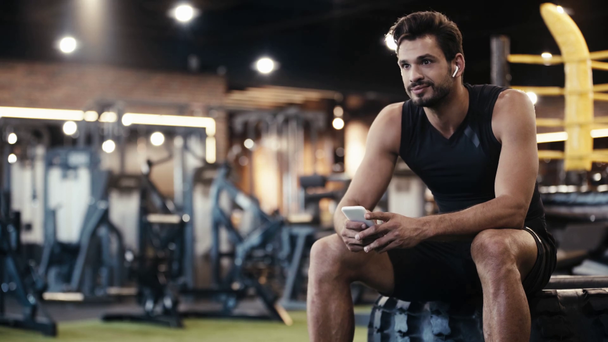 Glücklicher Sportler hört Musik im Fitnessstudio  - Filmmaterial, Video