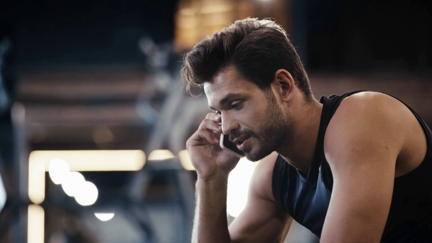 smiling sportsman talking on smartphone in gym  - Кадри, відео