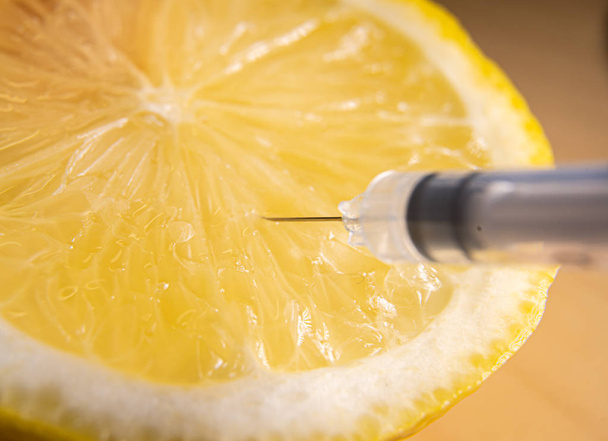 Syringes or needles extracting vitamin C from lemon. - Photo, Image