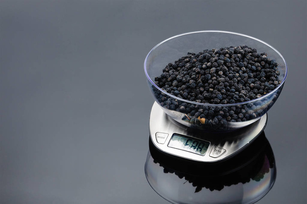 Dry blackberry in bowl on an electronic scale on grey mirror bac - Photo, Image