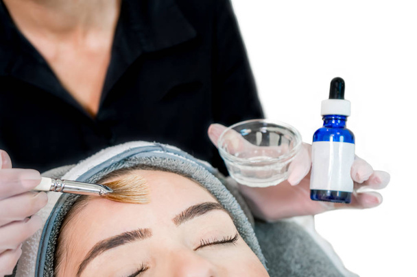 Gros plan de l'esthéticienne (cosmétologue) appliquant un traitement chimique de la peau sur le patient dans un spa de beauté, pour le rajeunissement de la peau, les soins de beauté du teint et de l'acné
. - Photo, image