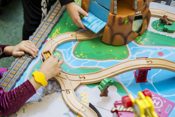 Dziecko chłopiec bawi się drewnianą zabawką, buduje koleje zabawki w domu lub przedszkolu - Zdjęcie, obraz