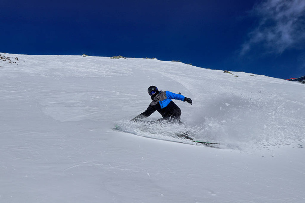 Профессиональный лыжник делает изгиб на порошковом снегу вниз по склону на фоне гор в Низких Татрах, Словакия. Концепция экстремального спорта во взрослом возрасте. Торможение в цель
 - Фото, изображение