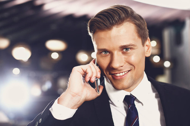 Laconic portrait of handsome young man talking on the phone and smiling - Foto, Imagen