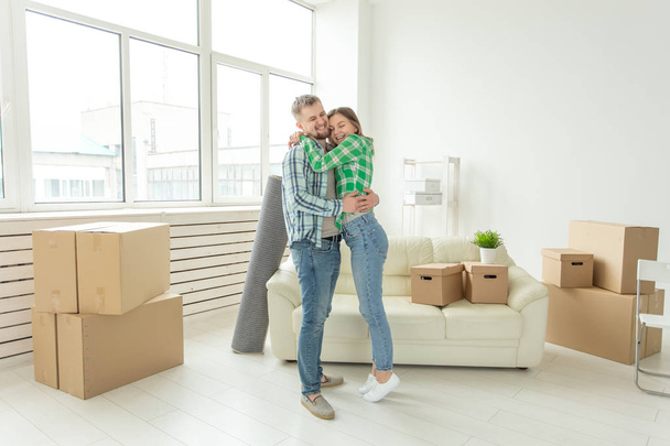 Loving young couple embracing rejoicing in moving to their new home. The concept of moving and housewarming of young family. - Foto, Imagen