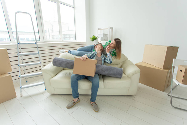 Jovem casal alegre se alegra em se mudar para uma nova casa que estabelece seus pertences na sala de estar. Conceito de aquecimento doméstico e hipotecas para uma família jovem
 - Foto, Imagem