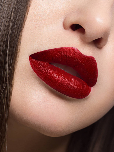 Macro photo of plump lips with bright red matte lipstick. Clean skin, lip injections. Evening fashion makeup closed mouth - Fotografie, Obrázek