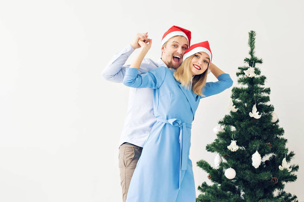 Christmas tree and holidays concept - Happy smiling family wearing santa hats celebrating at home. - Foto, Bild