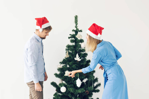 Árbol de Navidad y el concepto de vacaciones - Feliz familia sonriente con sombreros de santa celebrando en casa
. - Foto, imagen