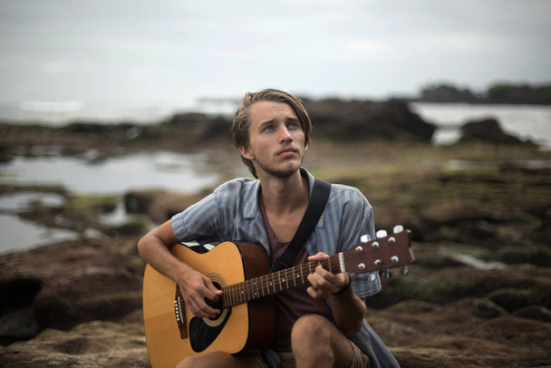 Romantyczny młodzieniec z gitarą na plaży - Zdjęcie, obraz